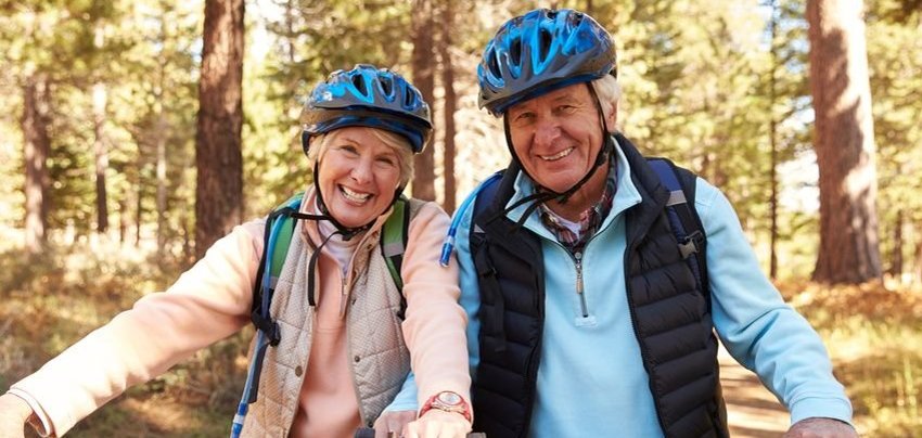 Senior couple on mountain bikes in a forest, portrait