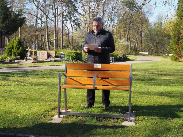 Beig. Hans Schwind an gespendeter Bank, Friedhof