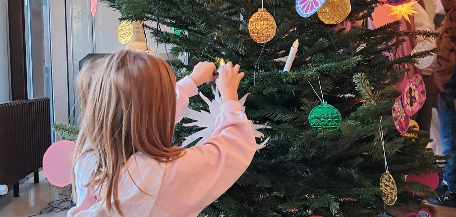 Kind schmückt einen Weihnachtsbaum